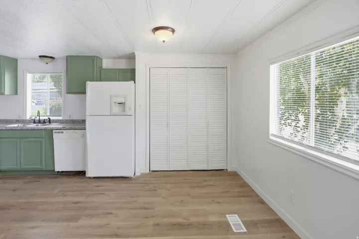 Kitchen area featuring sage green cabinetry, stone-finish countertops, and a stainless steel sink with a black faucet