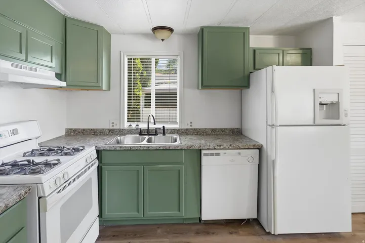Kitchen featuring green cabinetry, a dual basin stainless steel sink with a black-finish faucet, and laminate countertops