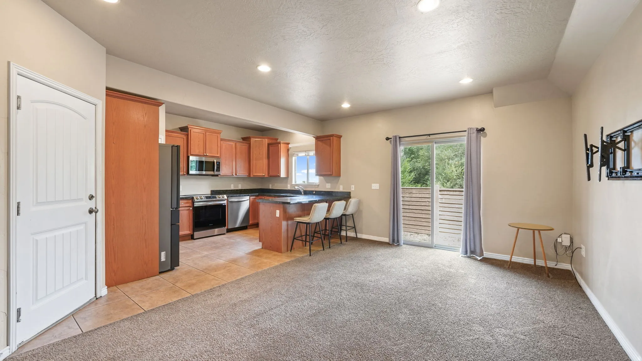 Open concept living area featuring a kitchen with wood cabinetry and stainless steel appliances