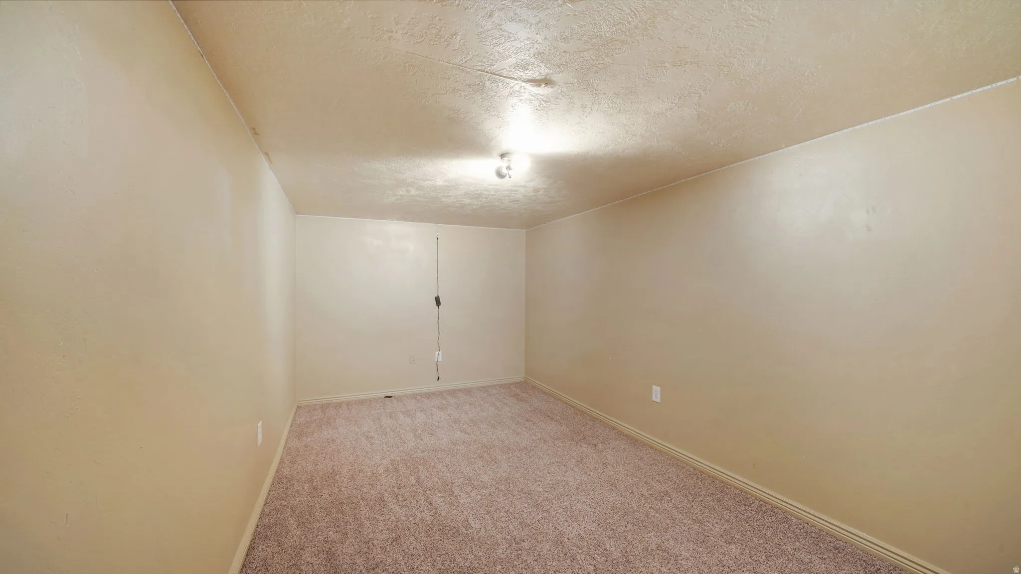 Carpeted room featuring light beige wall paint, a textured ceiling, and a flush-mount ceiling light fixture