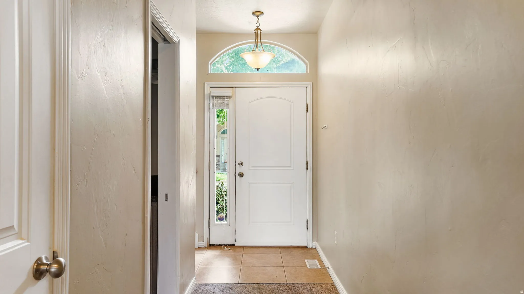 Entryway featuring a white paneled door, a decorative arched transom window, and a sidelight with privacy blinds