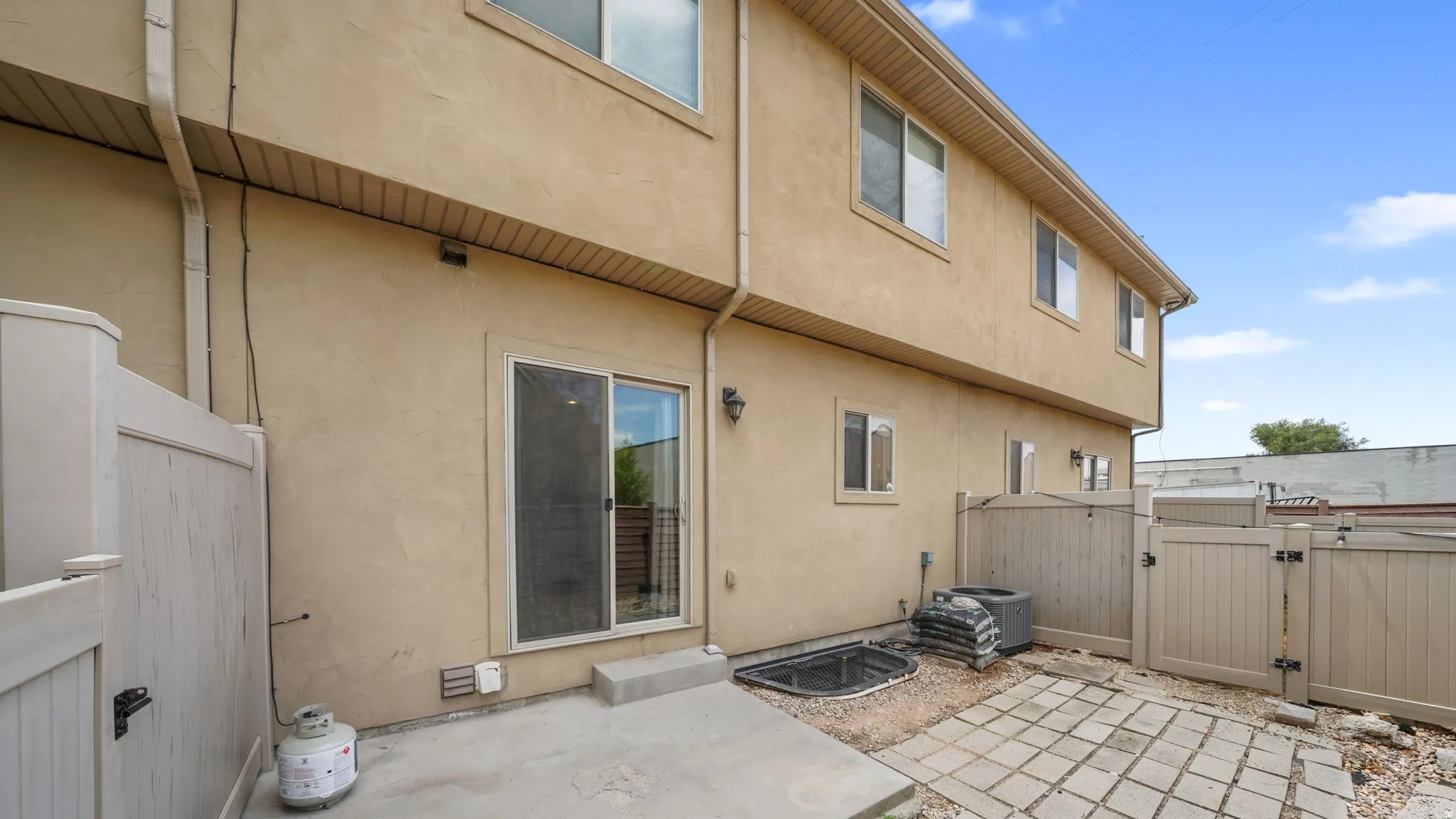 Private outdoor patio featuring a concrete slab, paver stones, and privacy fencing