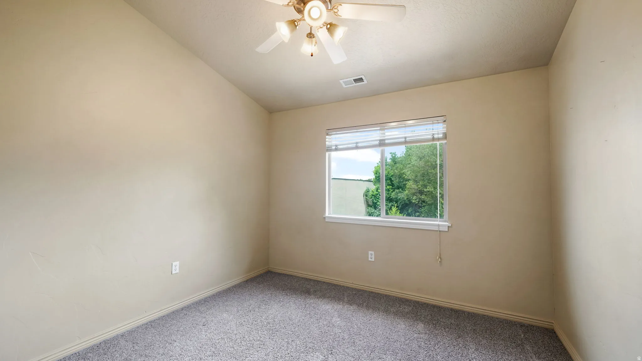 Carpeted room featuring a ceiling fan with integrated lighting, a window with horizontal blinds, and vaulted ceilings