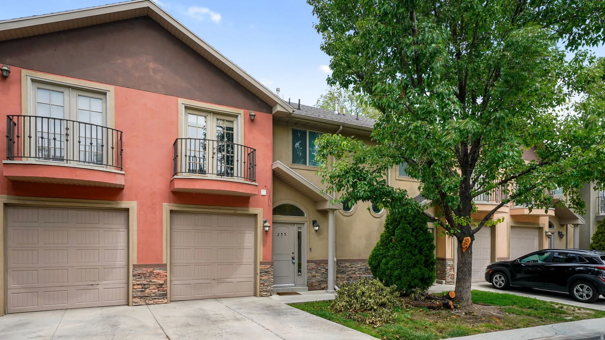 Tuscan-inspired multi-story residence with a stucco exterior, two integrated garages, and two Juliet balconies with wrought iron railings