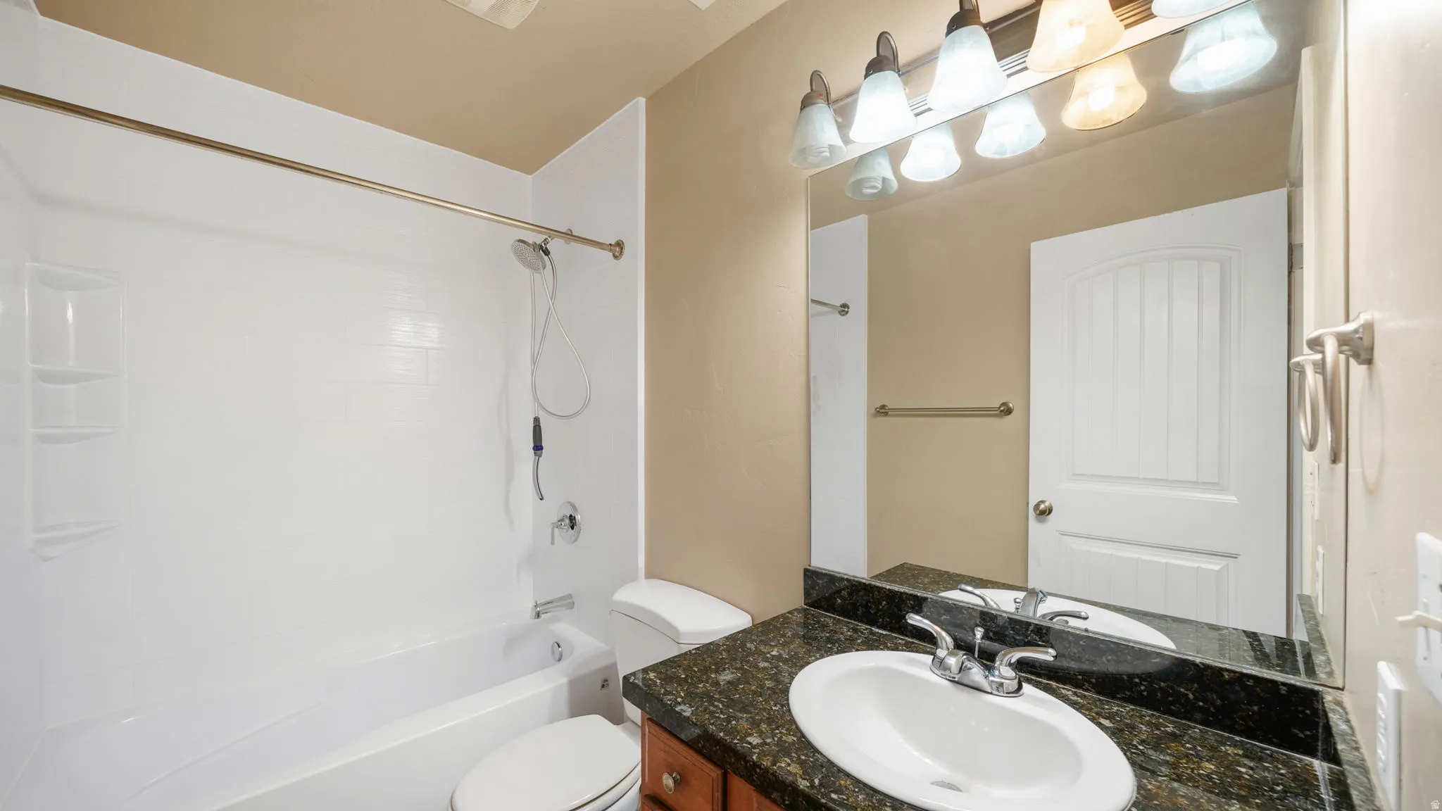 Bathroom featuring a vanity with a dark granite countertop, an undermount sink, and a brushed nickel faucet