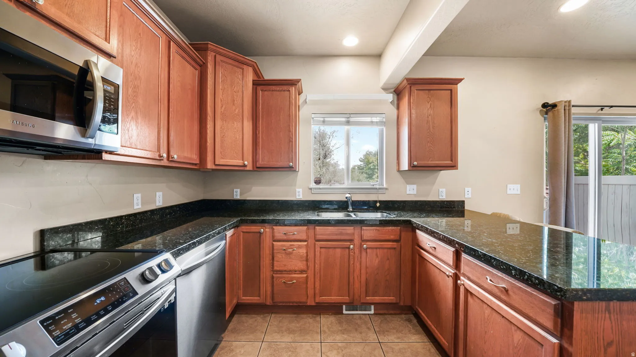 U-shaped kitchen featuring wood cabinetry and dark countertops