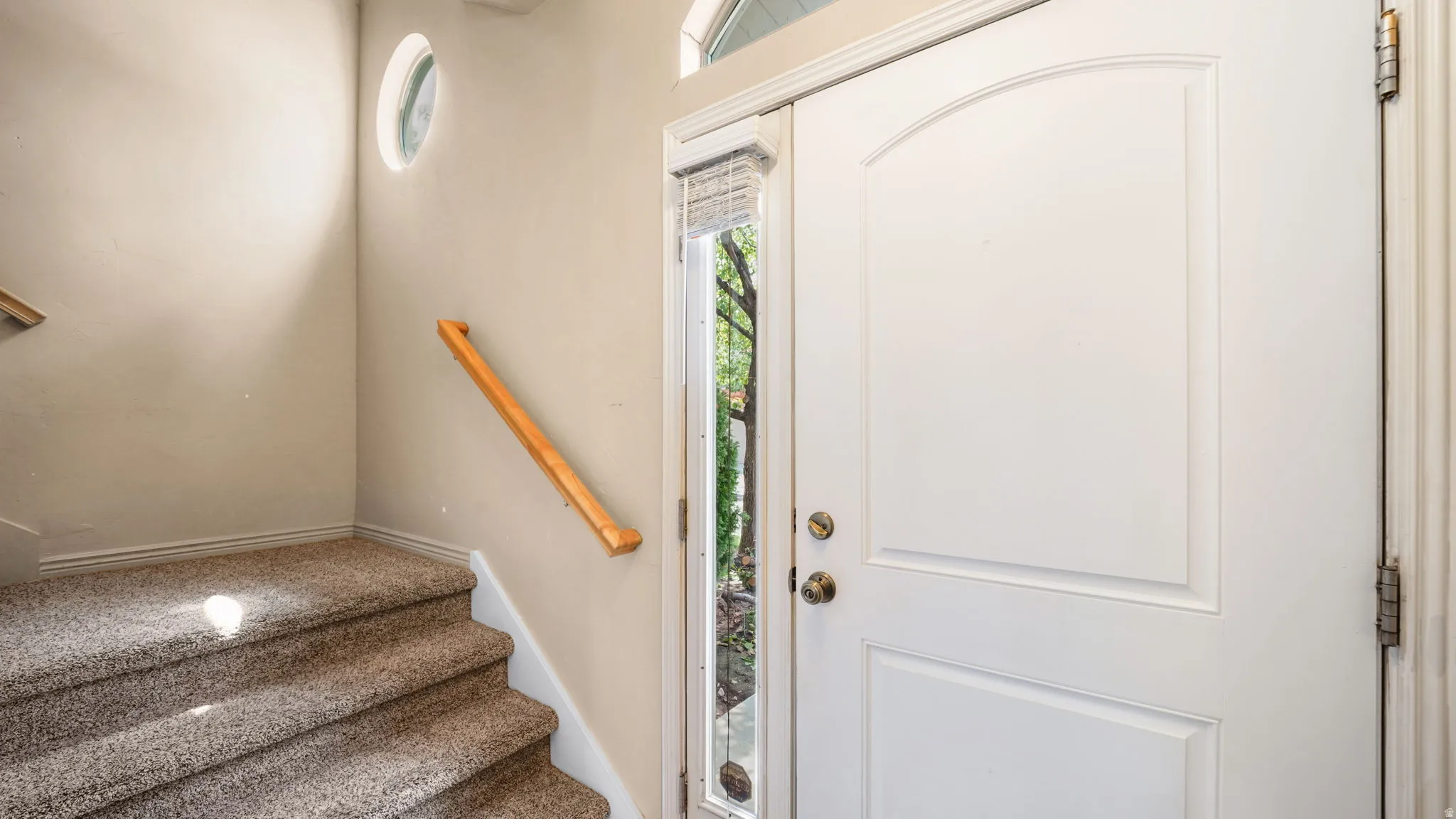 Entryway featuring a white paneled door with an arched top window, a full-length sidelight, and a round accent window