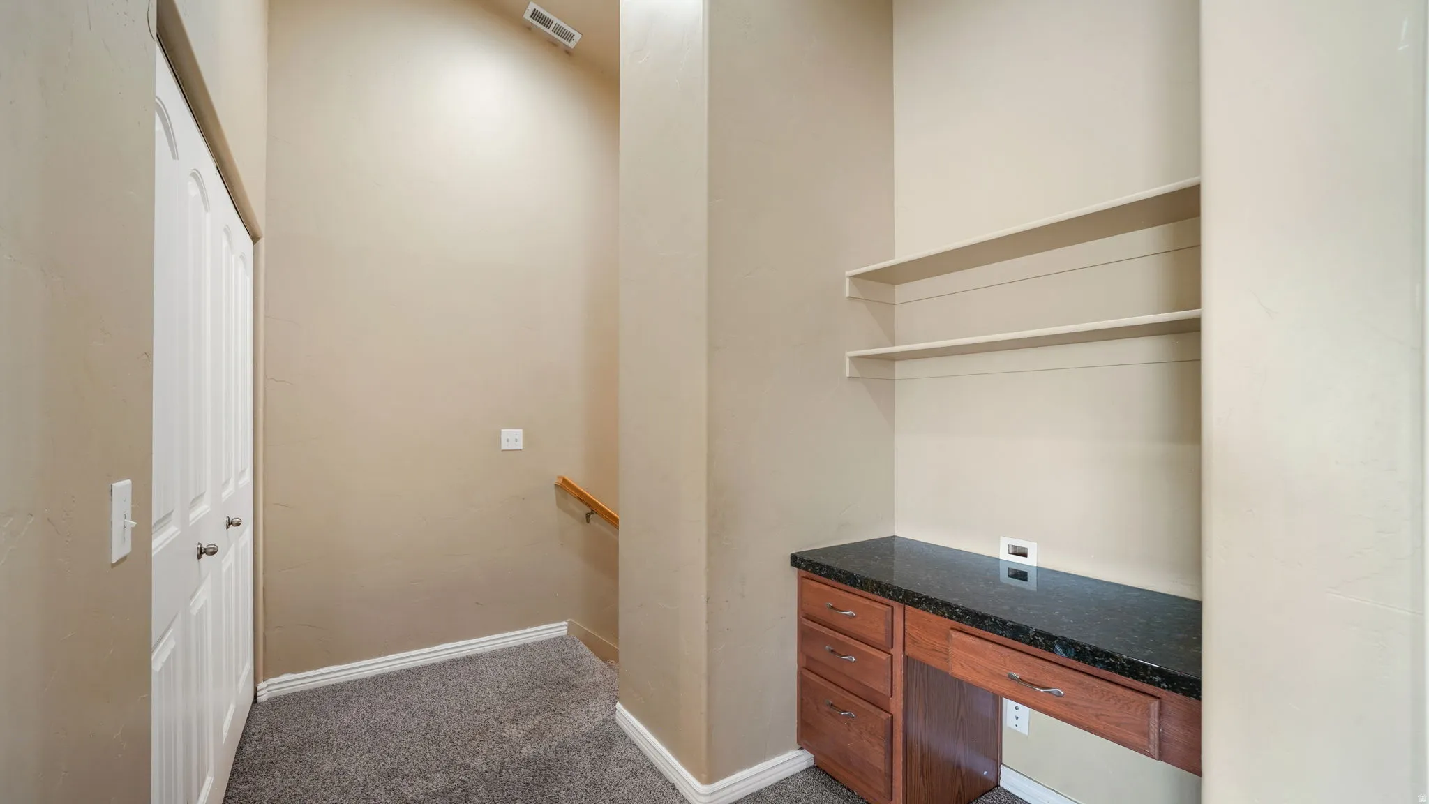 Built-in desk with a dark countertop and wood-finish cabinetry, complemented by open shelving