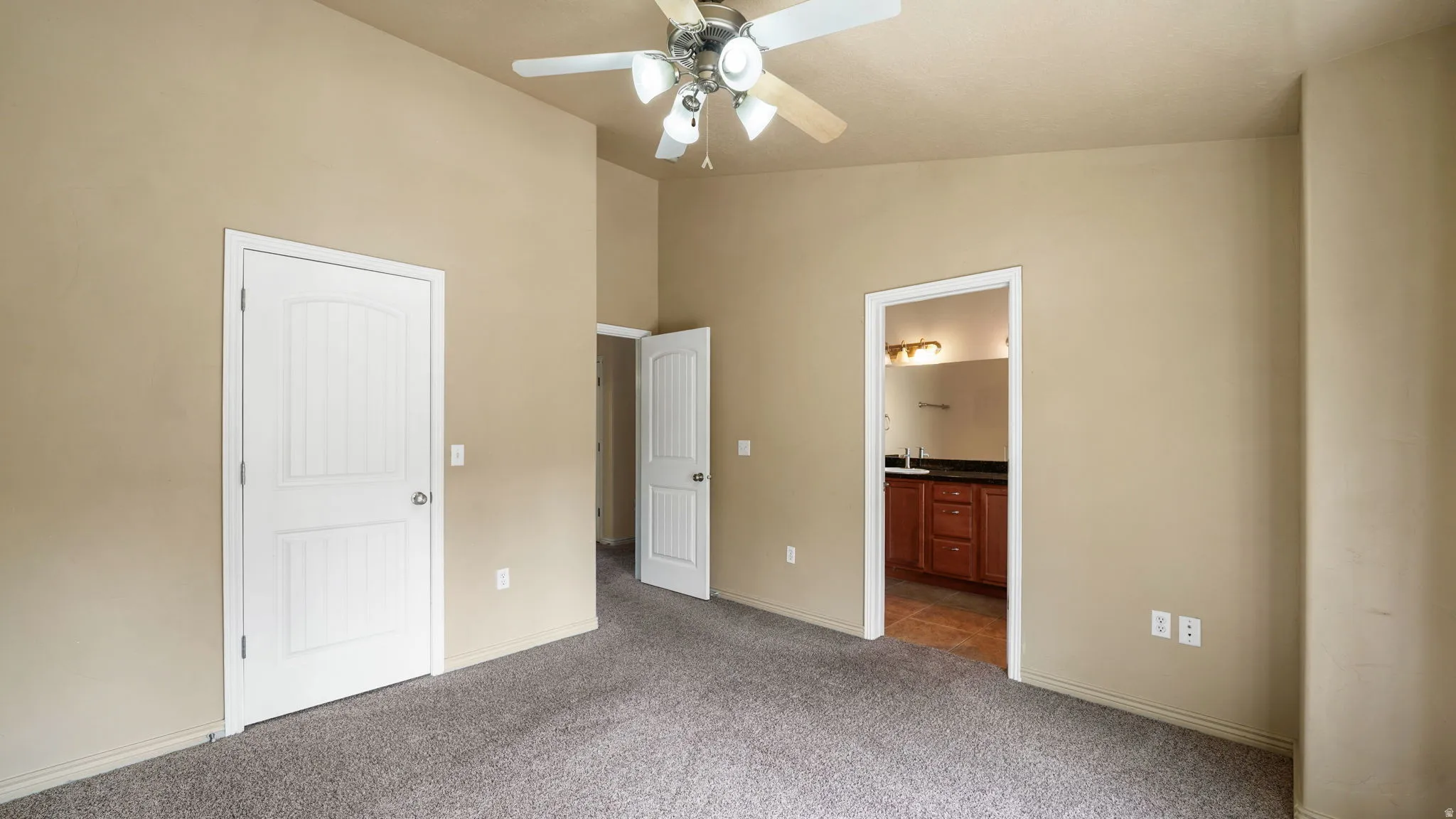 Carpeted room with vaulted ceiling and a ceiling fan with light fixture