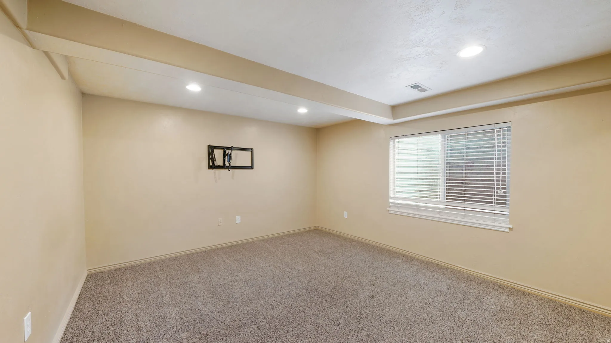 Carpeted room featuring recessed lighting, a window with horizontal blinds, and a wall-mounted bracket