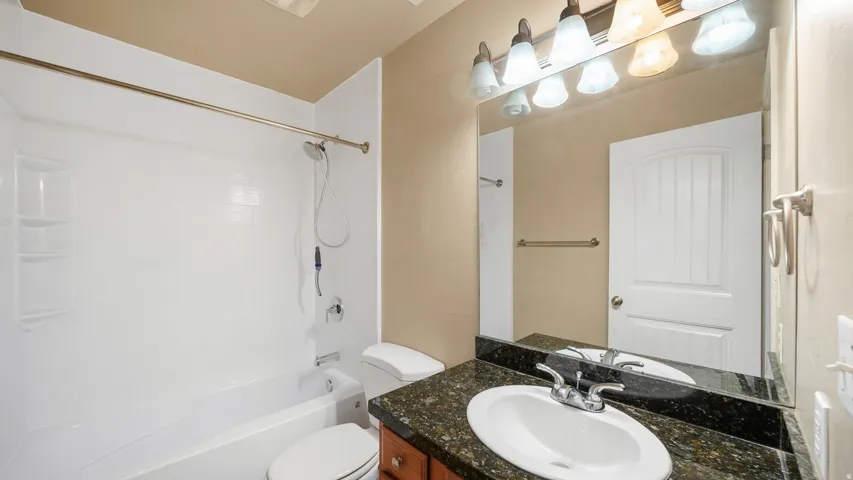 Bathroom featuring a vanity with a dark granite countertop, an undermount sink, and a brushed nickel faucet