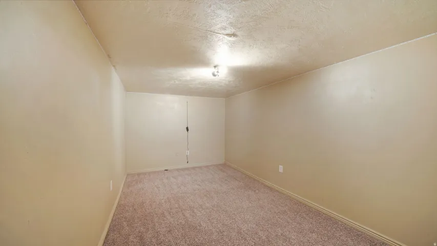 Carpeted room featuring light beige wall paint, a textured ceiling, and a flush-mount ceiling light fixture