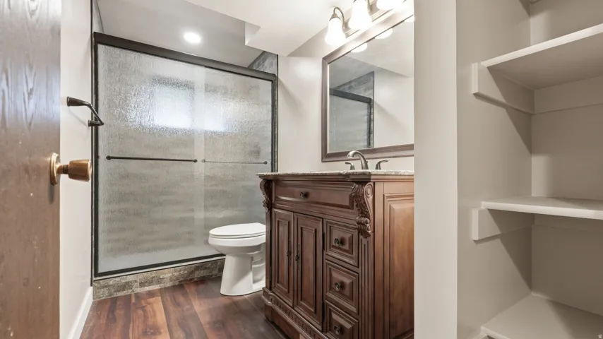Bathroom featuring a dark wood vanity with a stone countertop, a framed mirror, and a three-light vanity fixture