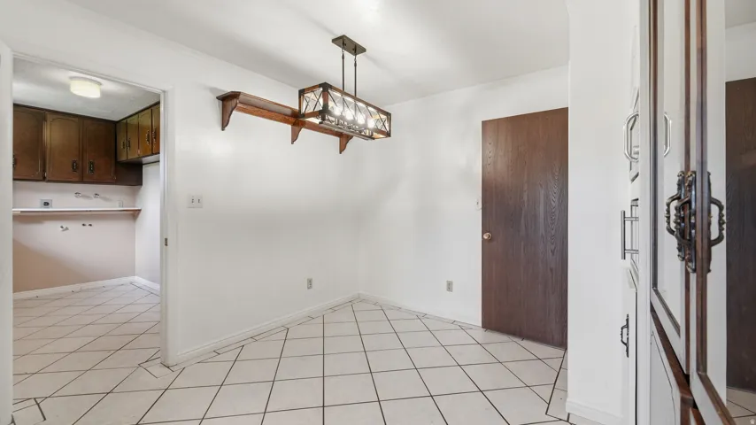Room featuring white walls, diagonal tile flooring, and a modern linear chandelier with a wood-finish frame
