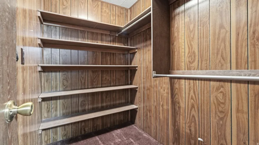 Closet interior featuring wood-finish paneling, built-in shelving, and metal hanging rods