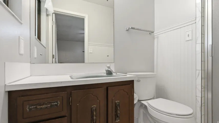 Bathroom with a wood-finish vanity, integrated sink, and a mirrored wall
