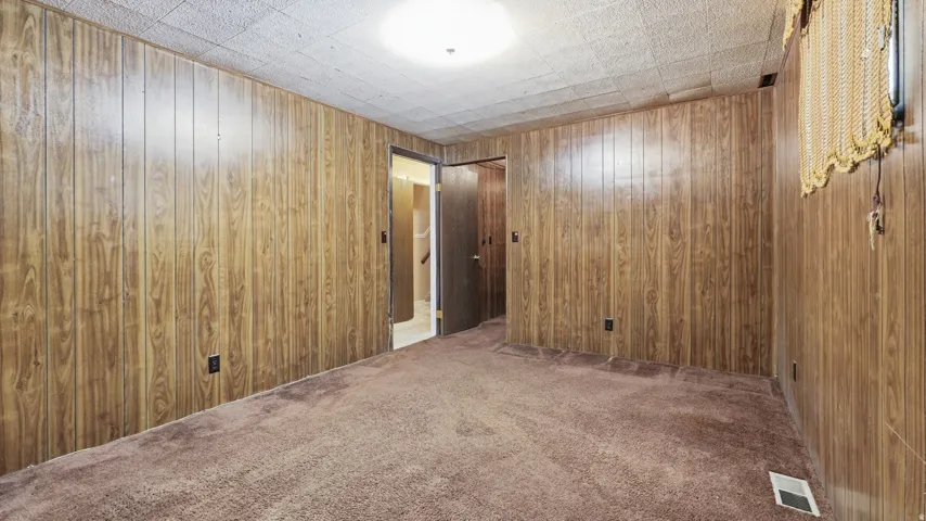 Carpeted room featuring wood-panel walls and a textured ceiling