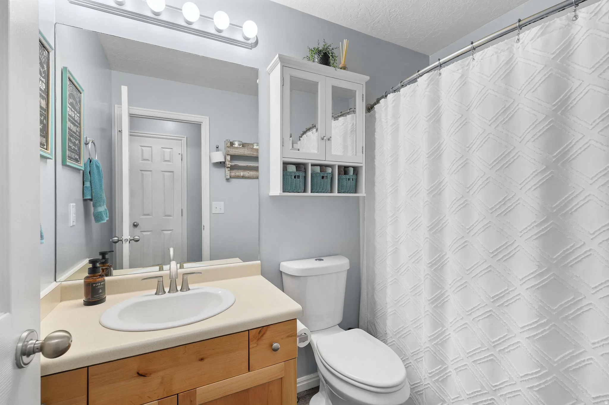Full hallway bathroom featuring a single vanity with wood-finish cabinetry, a large wall-mounted mirror, and a toilet