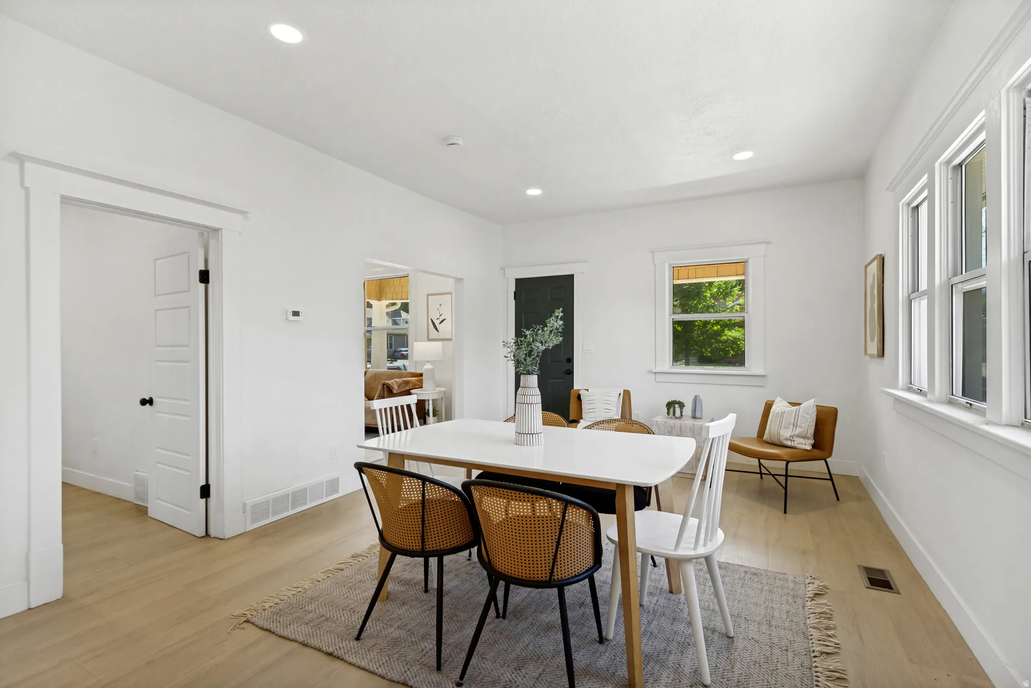 Open-concept space featuring light wood-finish flooring, white walls, recessed lighting, and ample natural light from multiple windows