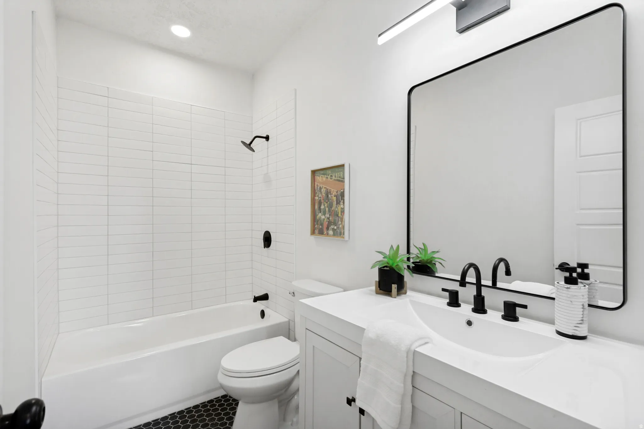 Bathroom featuring a single vanity with an integrated sink, matte black fixtures, a rectangular framed mirror, and a full bathtub with white subway tile surround