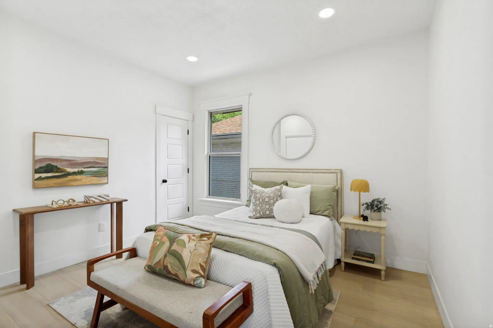 Bright interior space featuring light wood-finish flooring, recessed lighting, a window with exterior views, white trim, and a paneled door