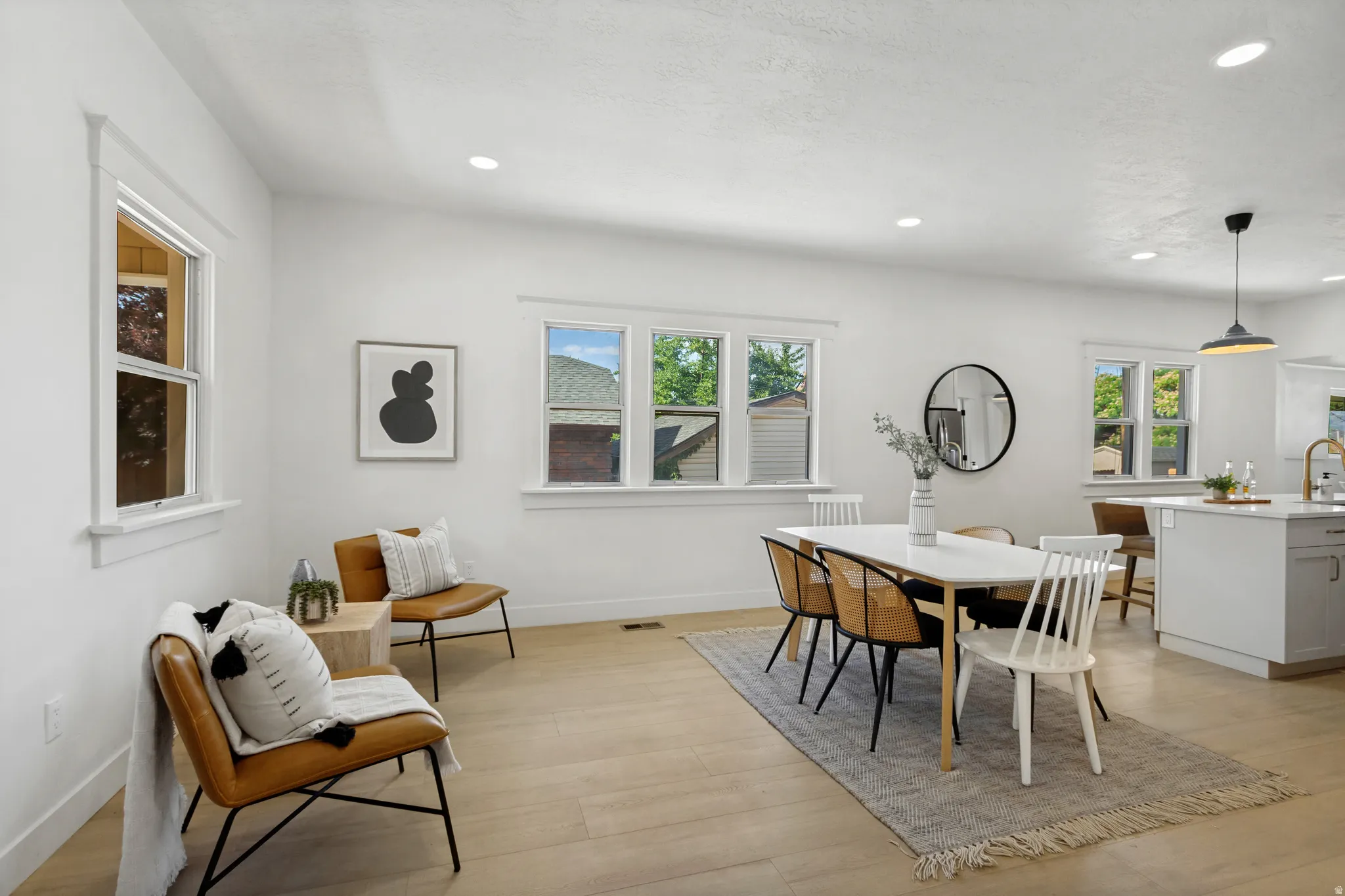 Open-concept living space featuring wood-finish flooring, recessed lighting, and multiple windows with white trim