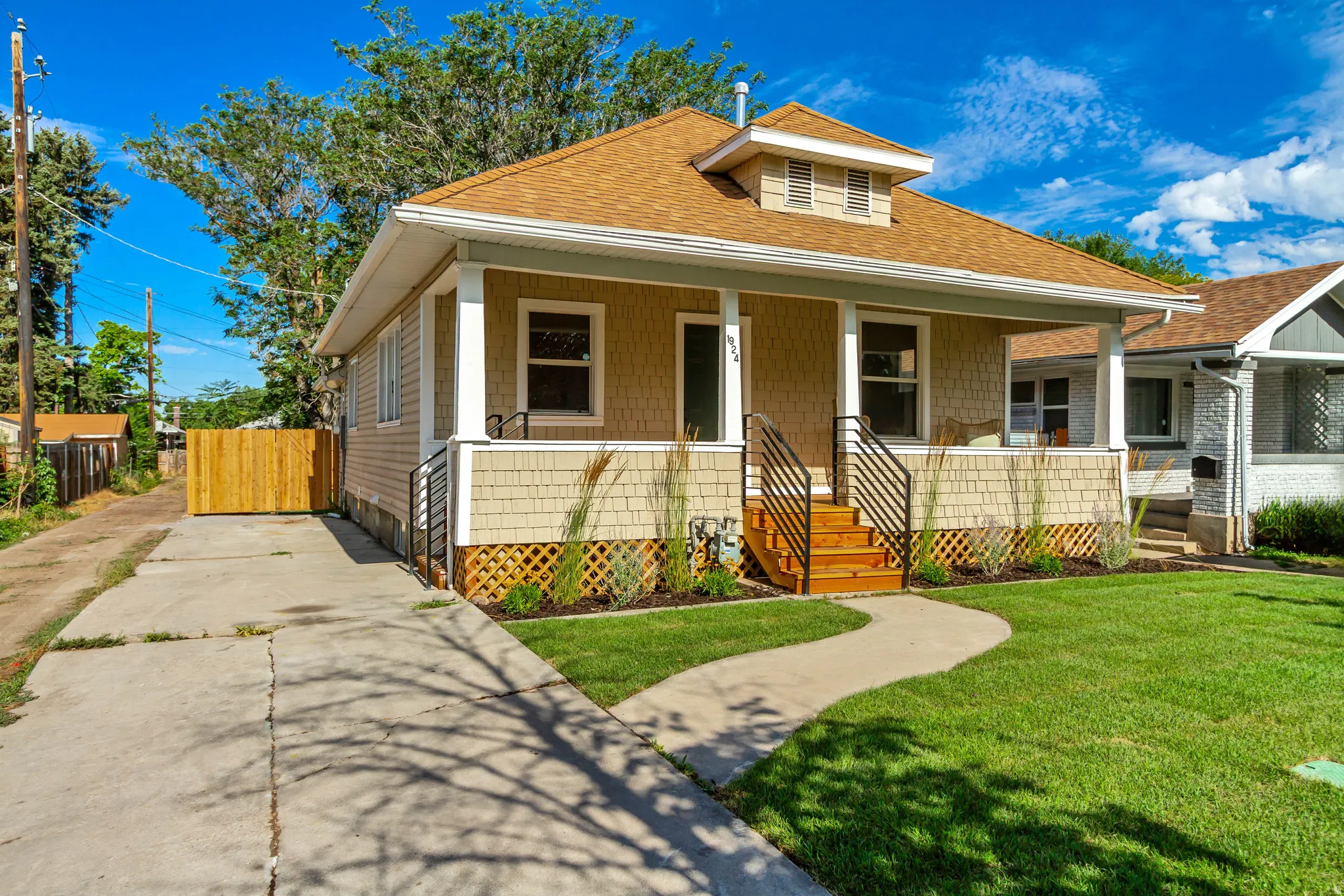 Craftsman-style home featuring a covered front porch, a light tan facade with shingle and horizontal siding, and a gabled roof