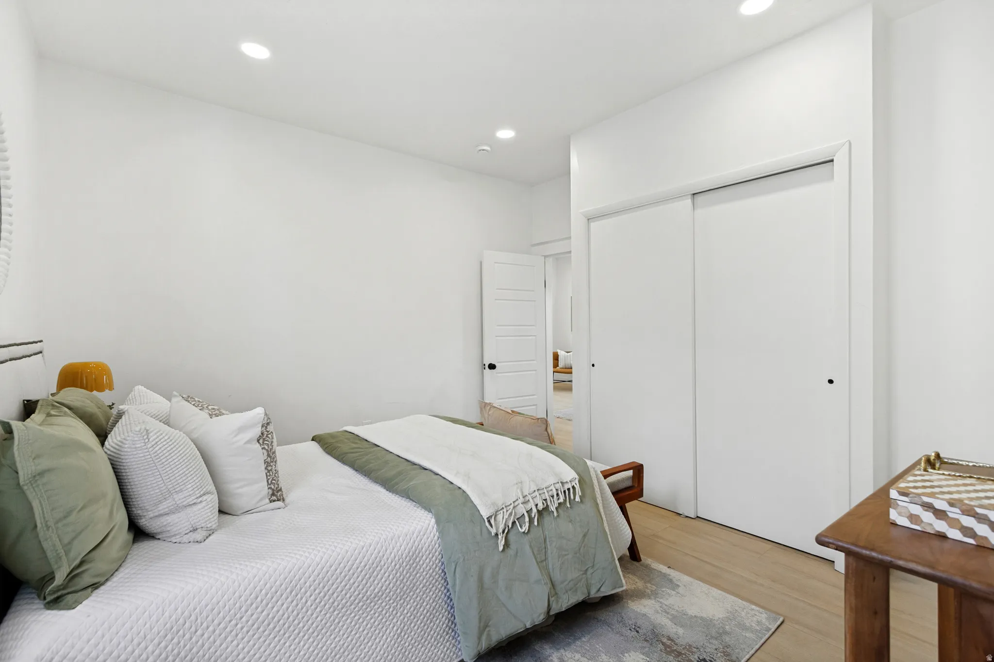 Bedroom featuring light wood-finish flooring, recessed lighting, and a white sliding closet door
