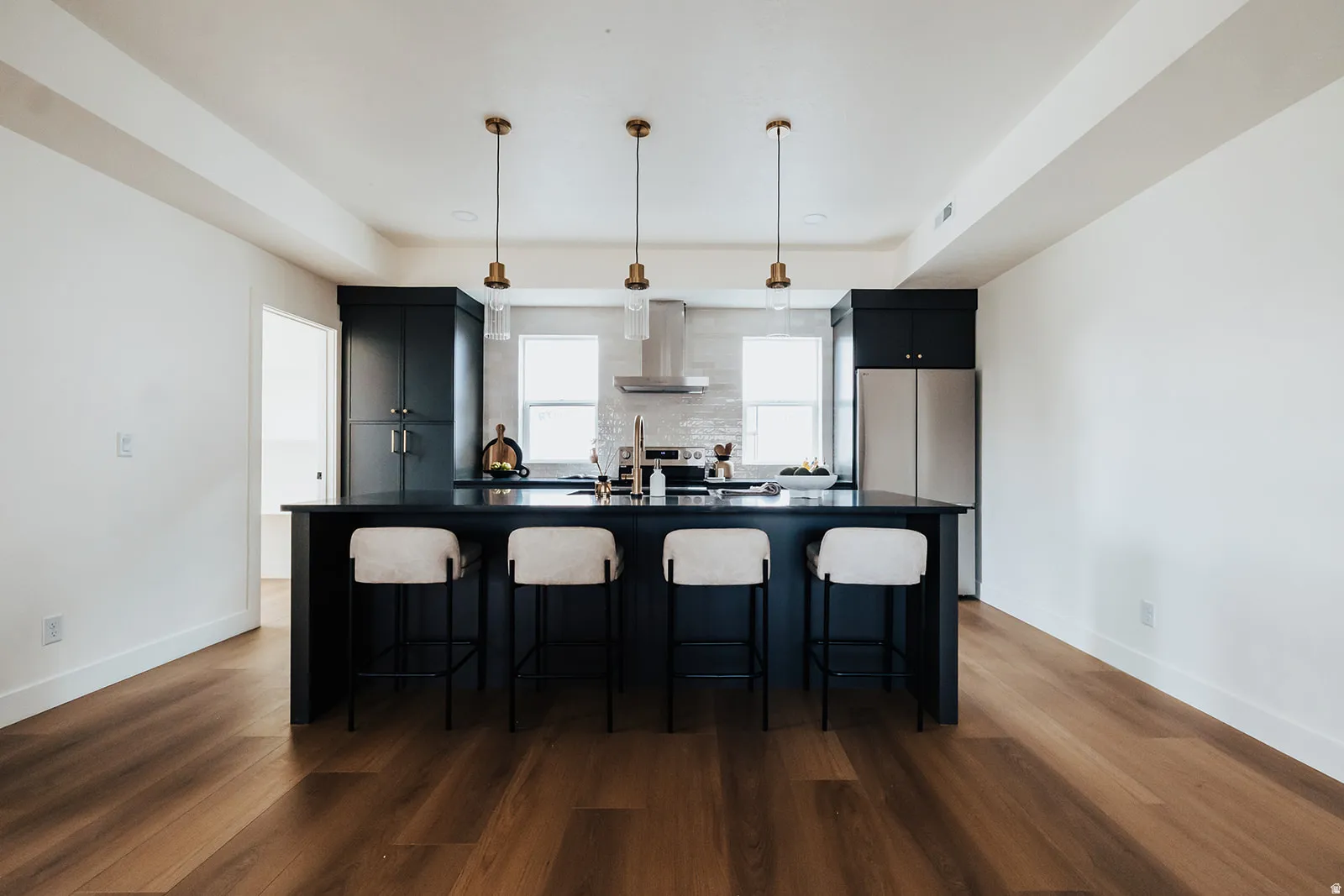 Open-concept kitchen featuring dark cabinetry, a spacious island with a dark countertop, and stainless steel appliances