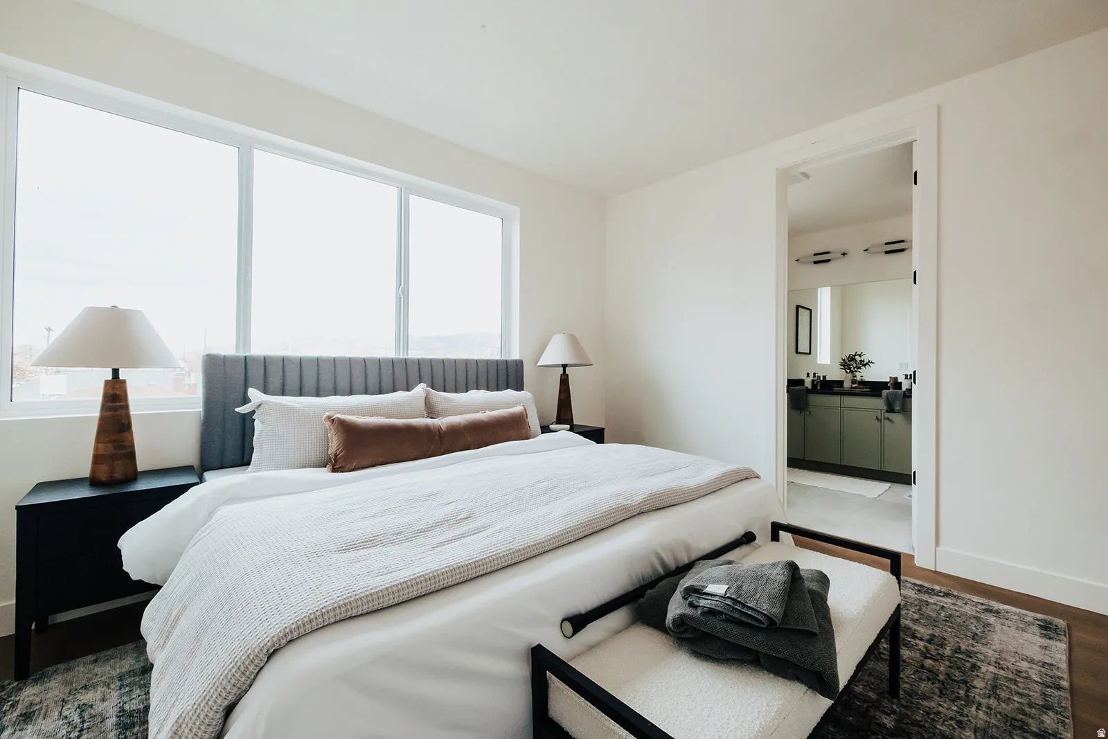 Bedroom featuring a series of three windows, wood-finish flooring, and light-toned walls