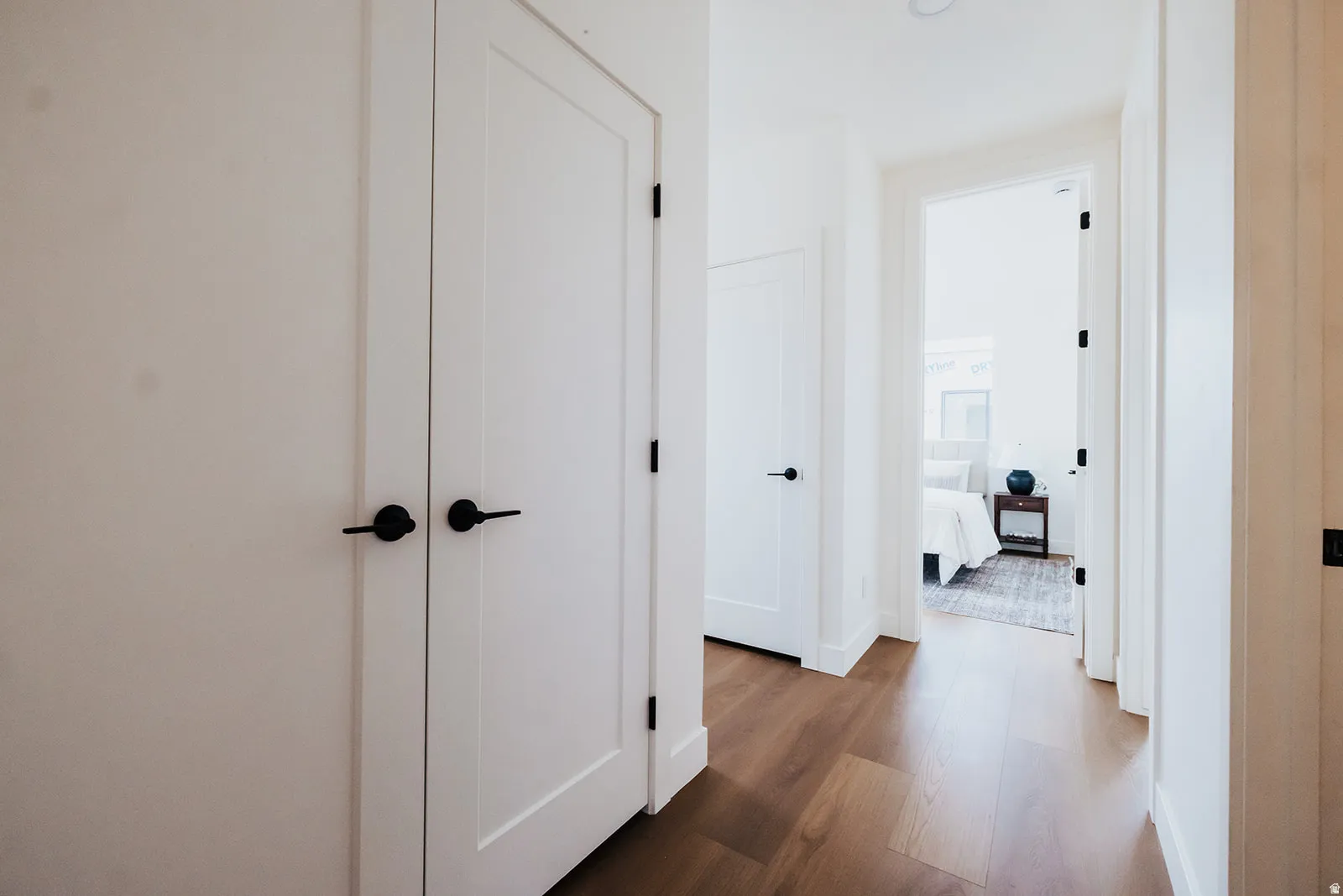Hallway featuring wood-finish flooring, white walls, and white trim