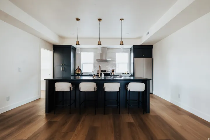Open-concept kitchen featuring dark cabinetry, a spacious island with a dark countertop, and stainless steel appliances