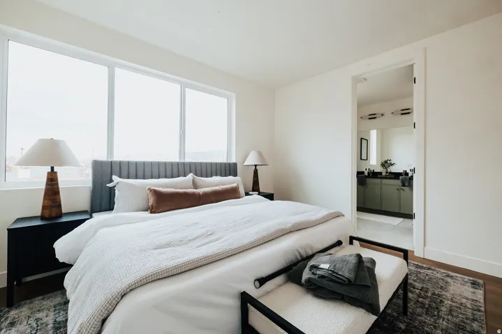 Bedroom featuring a series of three windows, wood-finish flooring, and light-toned walls