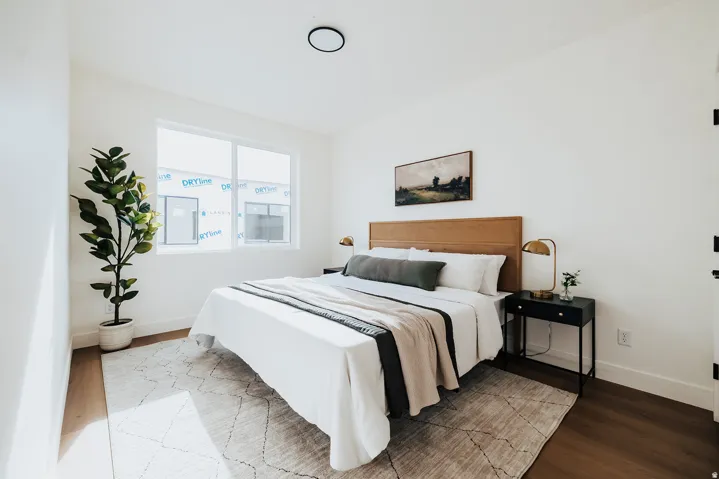 Spacious room with wood-finish flooring, white walls, and a large window
