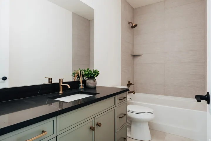 Bathroom featuring a sage green vanity with a dark countertop and an undermount sink