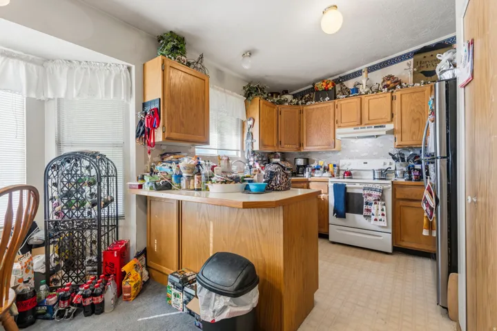 Kitchen featuring wood cabinetry, a center island with countertop, and white appliances