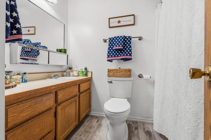 Bathroom featuring wood-finish vanity cabinetry with a light-colored countertop, an oval undermount sink, and a large wall-mounted mirror
