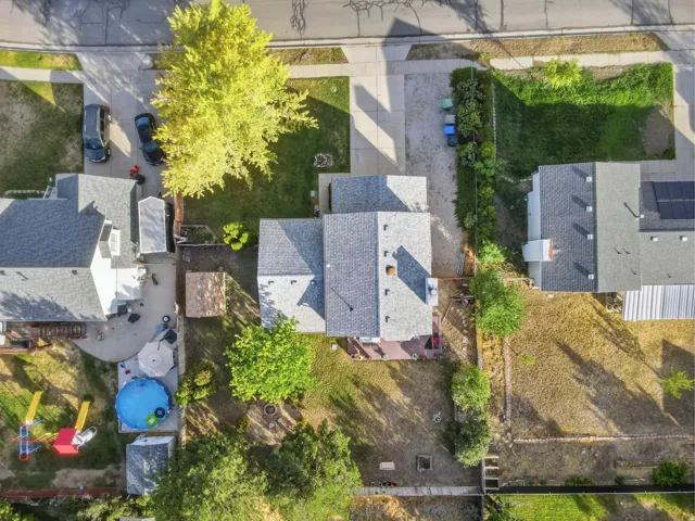 Overhead property depiction featuring a gray shingle roof, paved driveway, mature trees, and a spacious backyard