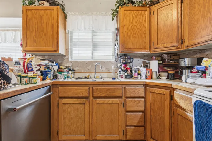 Kitchen featuring wood cabinetry, stainless steel dishwasher, and a window above the sink