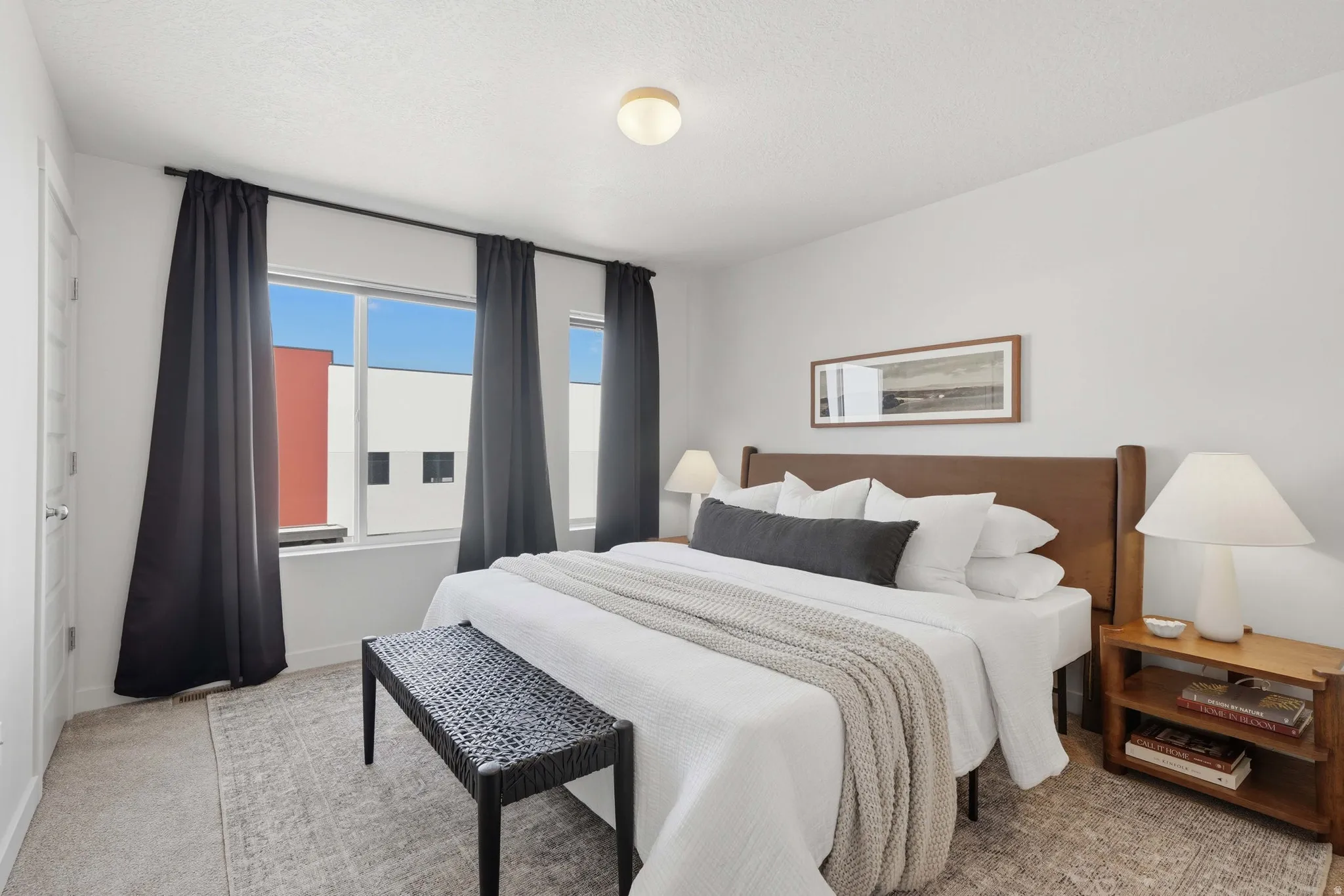 Bright bedroom with a wide window, neutral wall paint, and a textured area rug