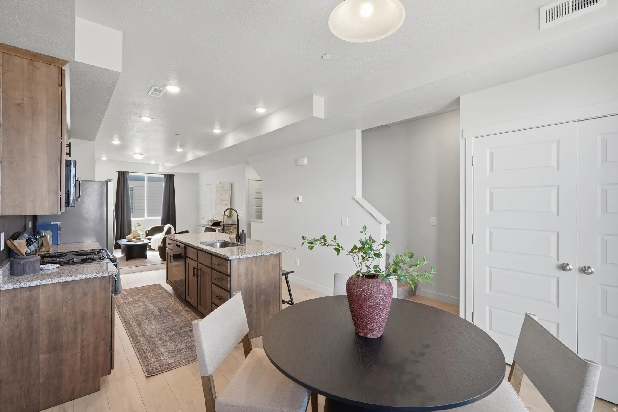 Open-concept kitchen and living area featuring light wood-finish flooring, recessed lighting, and white walls
