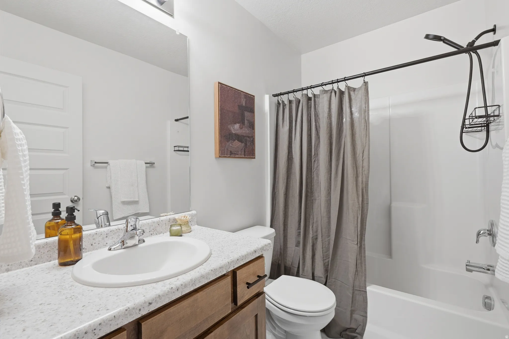 Bathroom featuring a white integrated sink, a speckled countertop, and a wood-finish vanity with dark hardware
