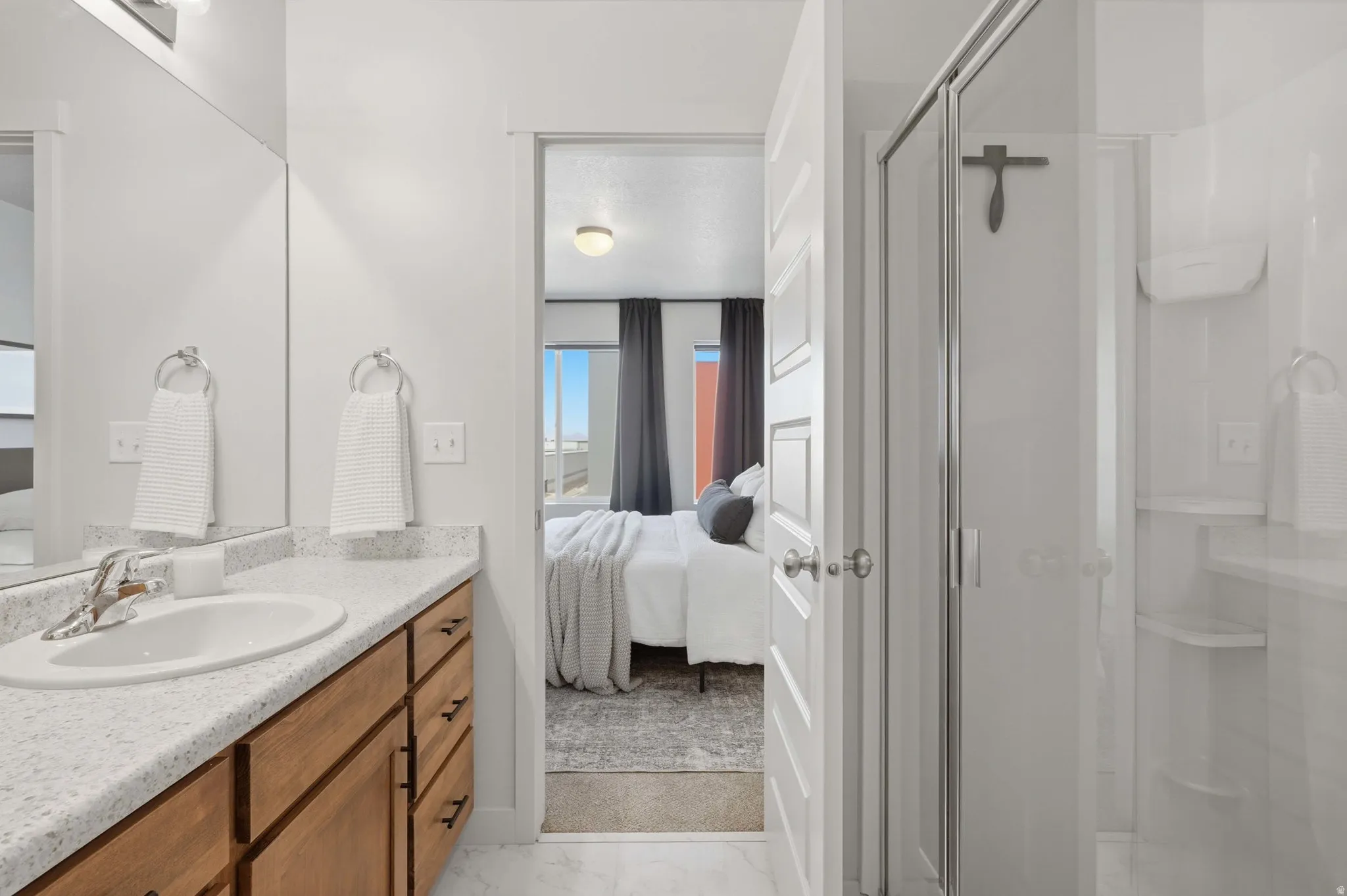 Bathroom featuring a wood-finish vanity with a speckled countertop, an integrated sink, and a mirrored wall