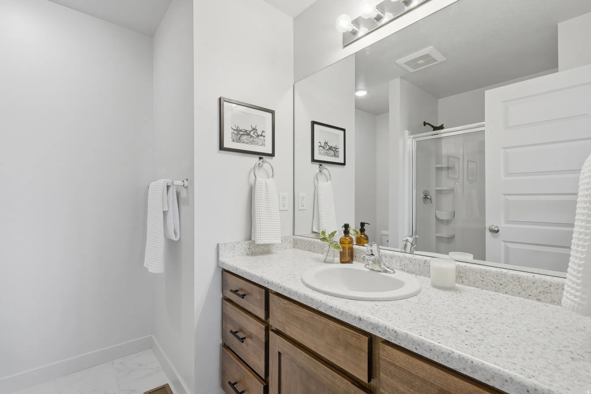 Bathroom vanity featuring a light-colored countertop, an undermount sink, and a wood-finish cabinet with dark hardware