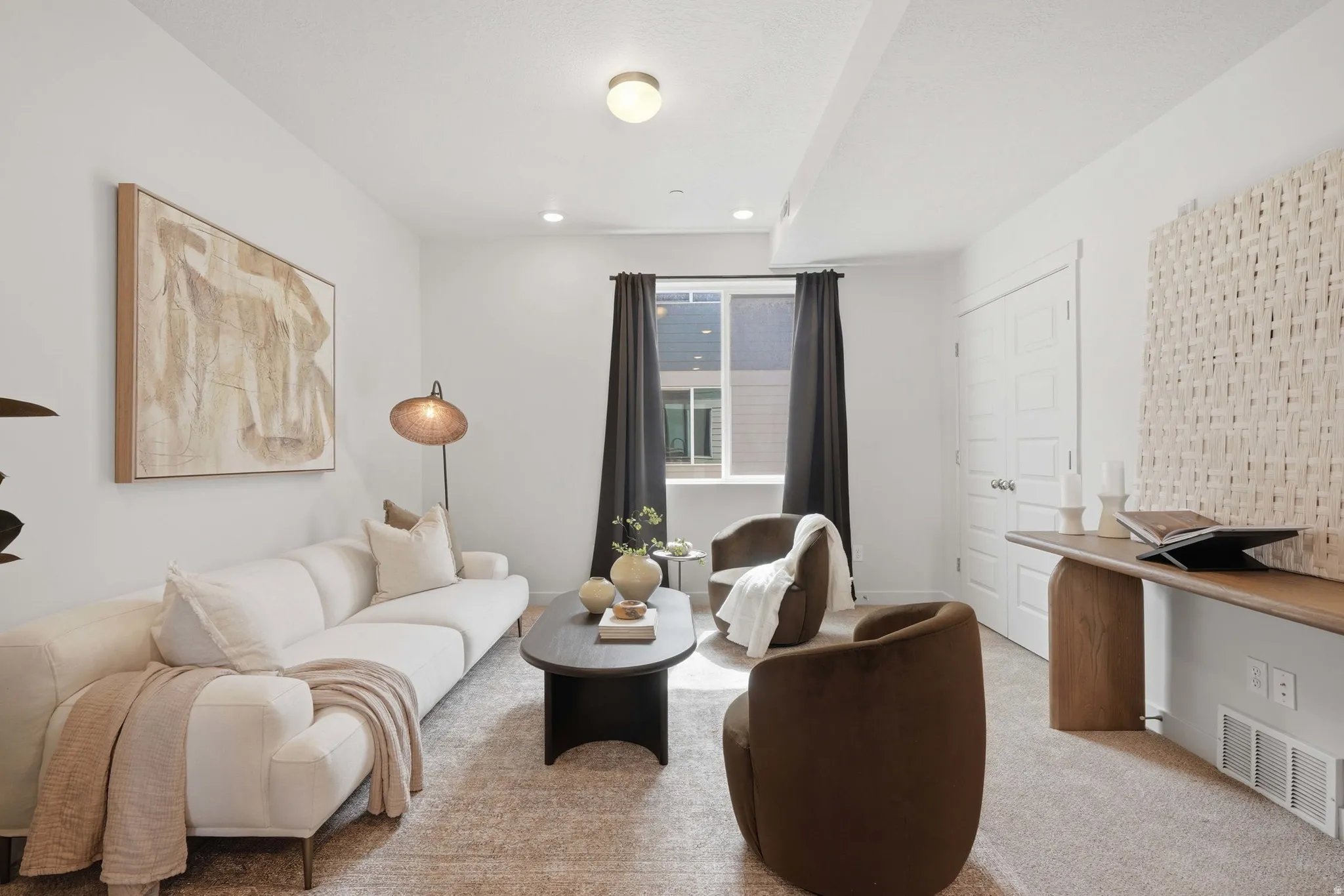 Brightly lit living area featuring recessed lighting, light-colored walls, a window with dark drapery, a textured area rug, and a built-in console table