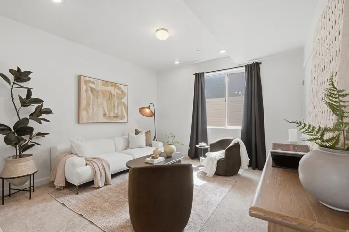 Bright living area featuring recessed lighting, a large window with dark drapes, and a decorative wall panel
