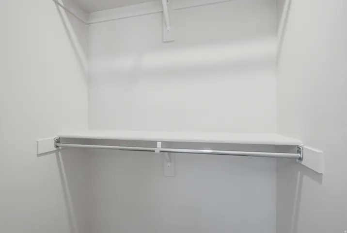 White-painted closet featuring a built-in shelf and chrome hanging rod