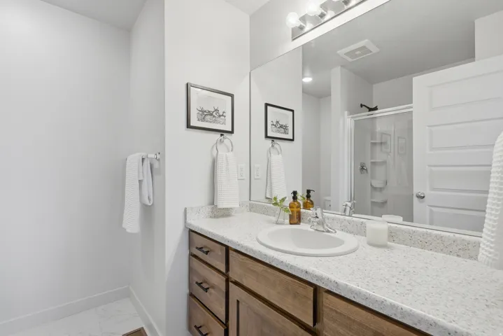 Bathroom vanity featuring a light-colored countertop, an undermount sink, and a wood-finish cabinet with dark hardware