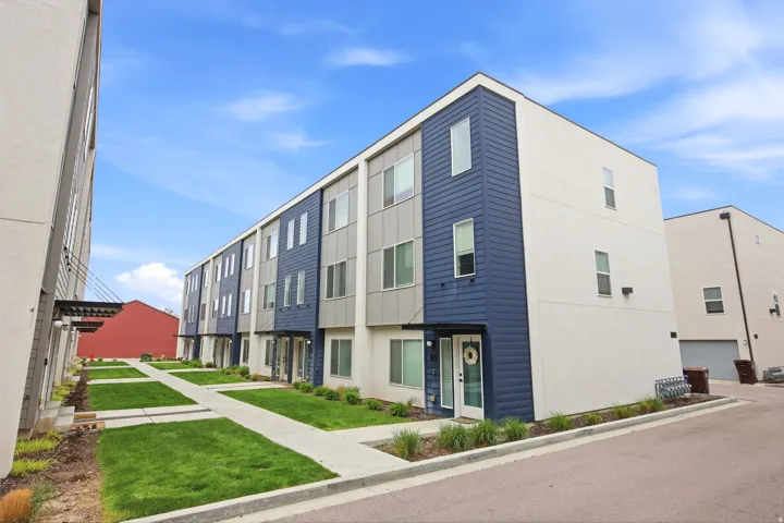 Modern multi-story facade featuring blue and gray siding with white stucco elements