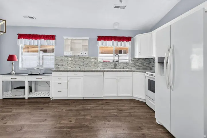 Kitchen featuring white cabinetry, stone-finish countertops, tile backsplash, and wood-finish flooring